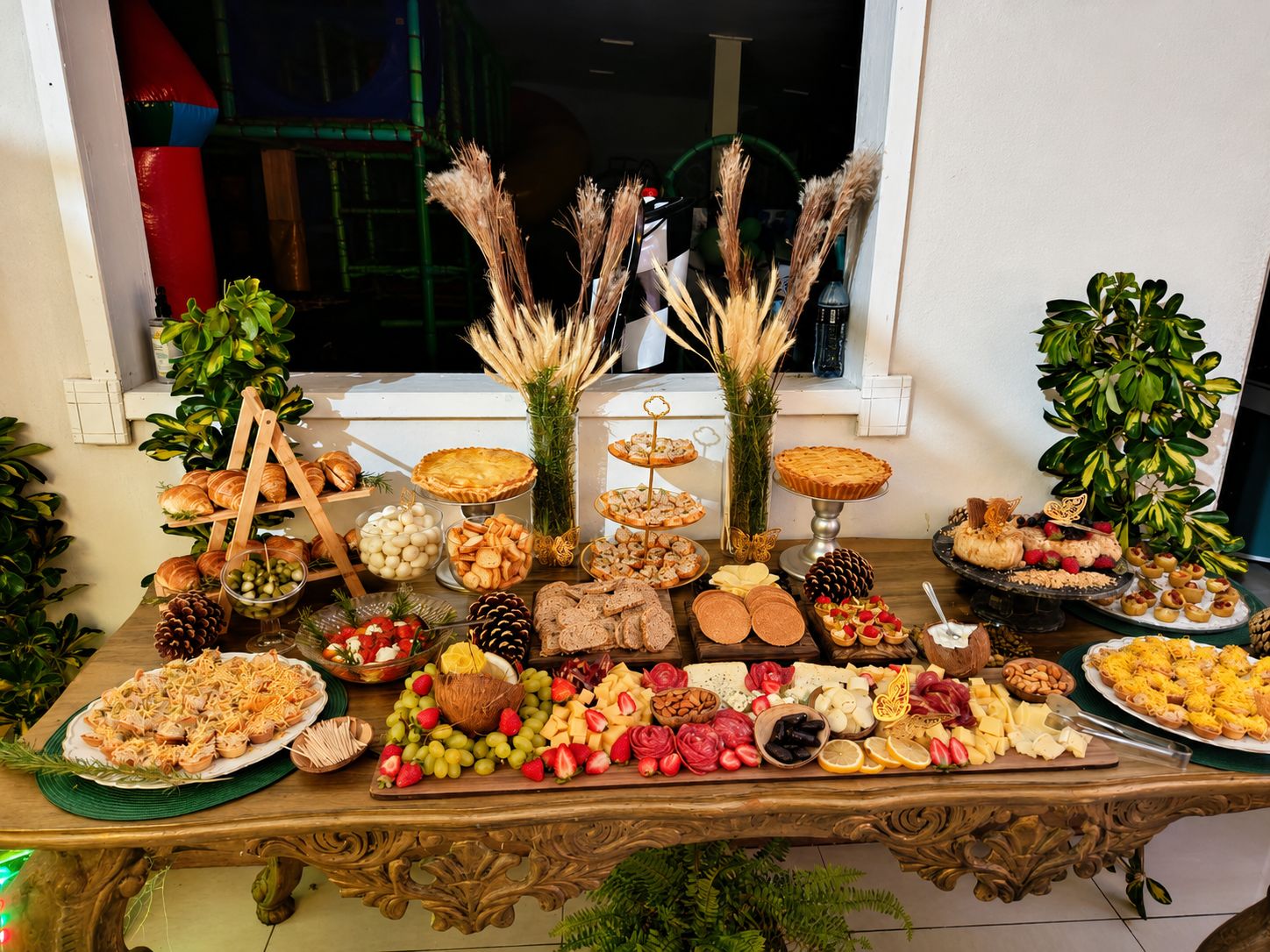 Mesa de evento montada com tábuas, doces, pães e finger foods